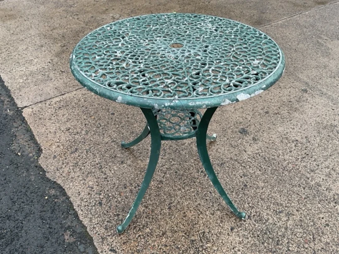 A circular painted metal garden table with pierced scrolled top on