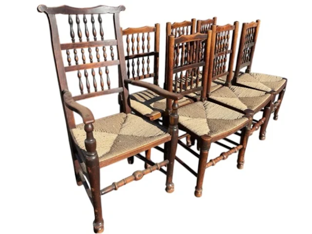 A set of seven antique oak rush seated chairs with spindled backs