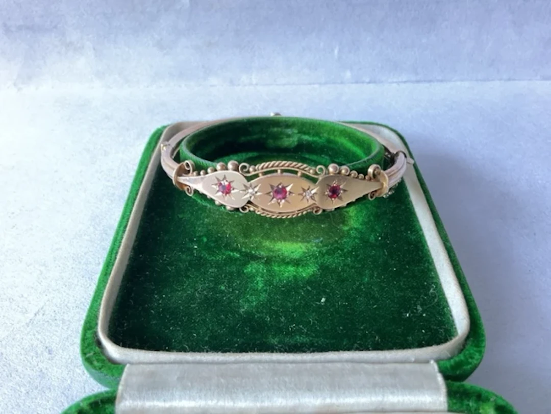 A boxed antique 9ct gold bangle with gypsy set rubies and diamonds. (7.68g)