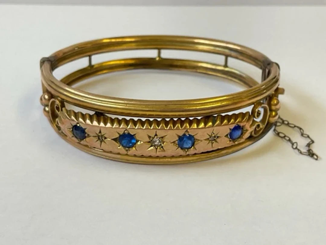 An antique 9ct gold bangle with gypsy set sapphires & diamonds on