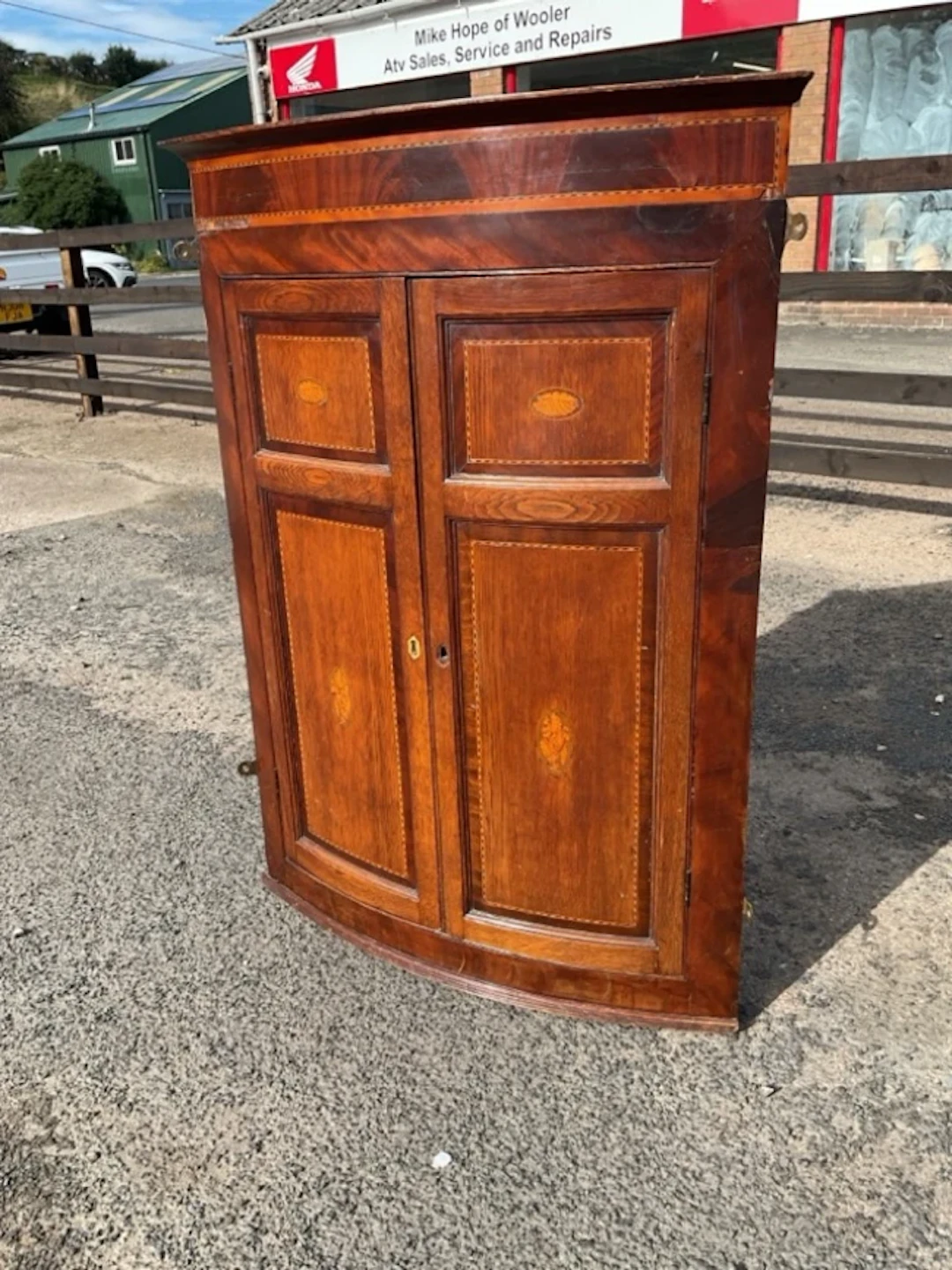 A nineteenth century bowfronted oak & mahogany corner cabinet inlaid