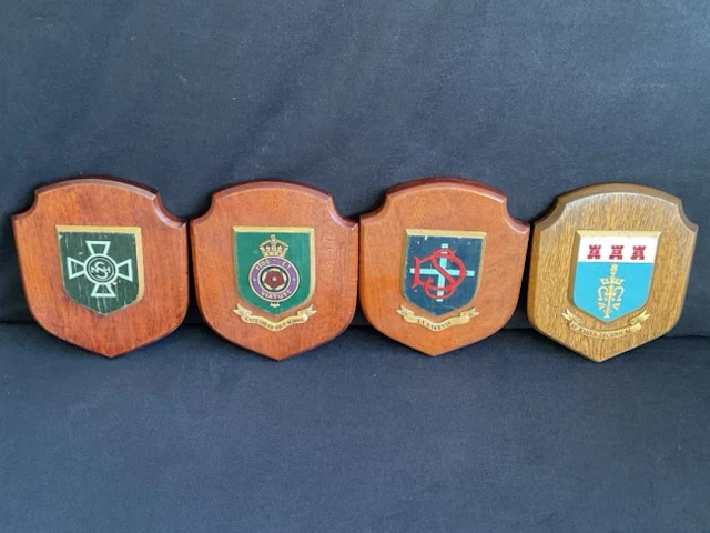 Four handpainted school shield plaques, three on mahogany and one