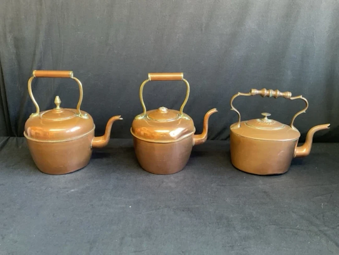 Three large Victorian copper kettles with swan-neck handles and shaped