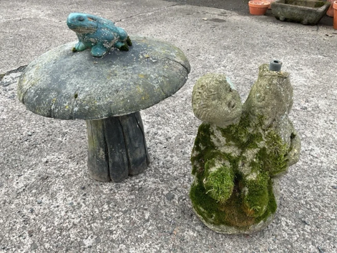 A composition stone garden ornament with cherub holding a fish - piped