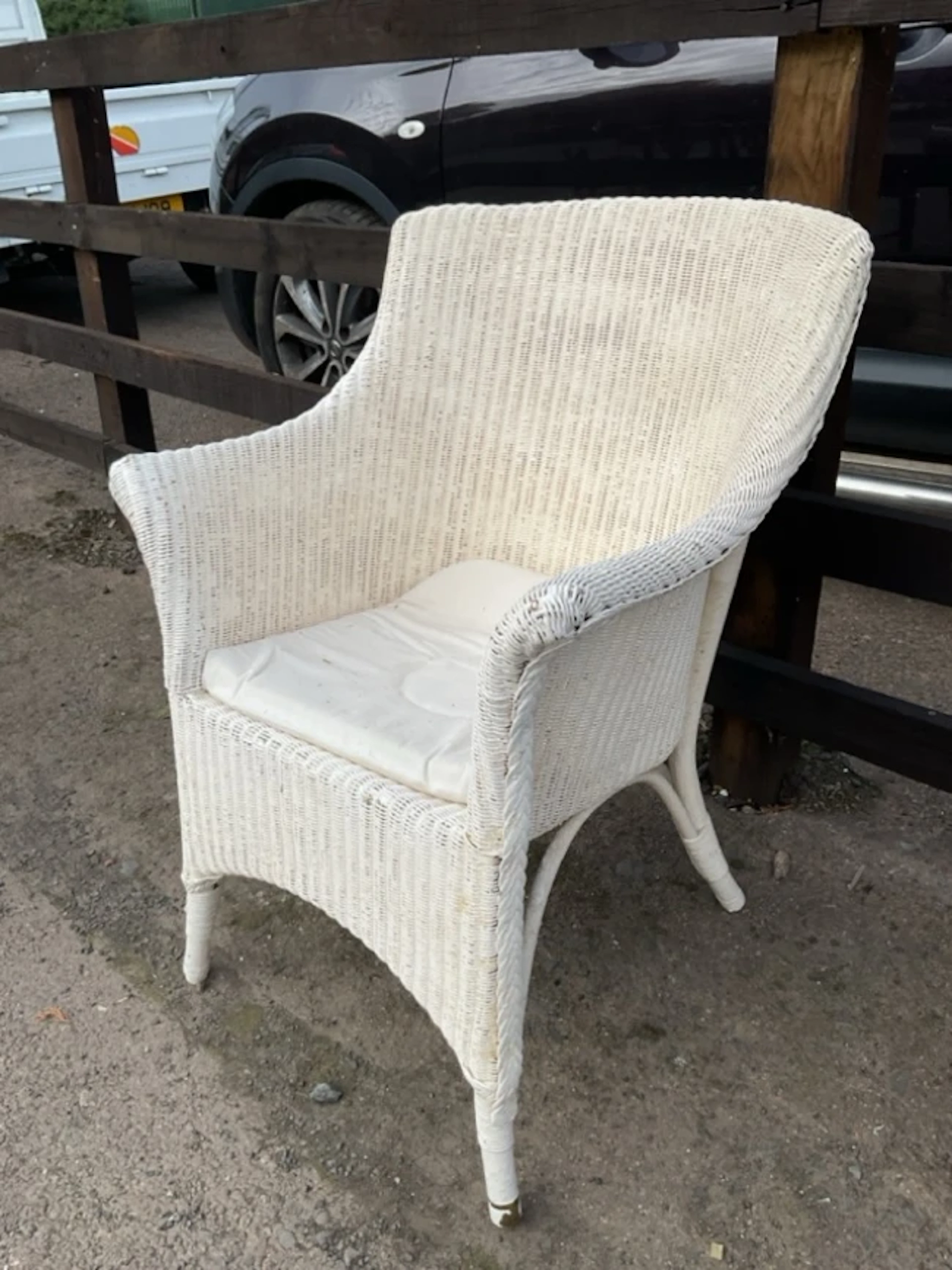A painted cane armchair with flared arms above a seat with loose cushion