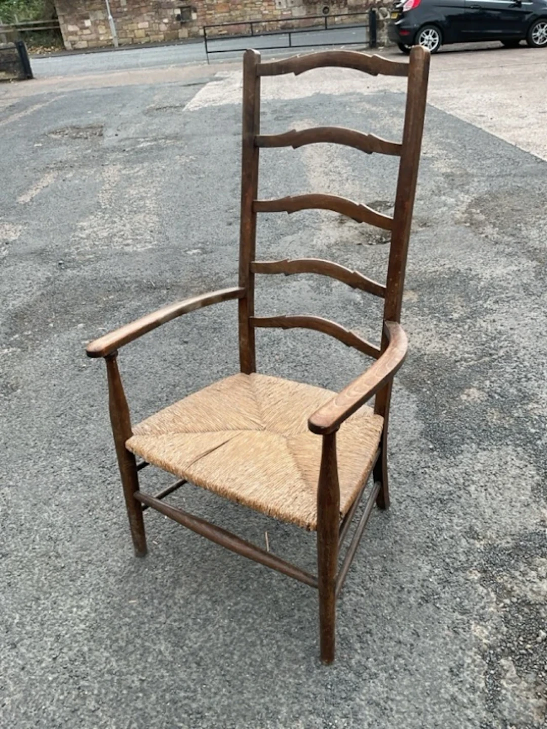 A rush-seated ladderback armchair with five shaped rails and rounded