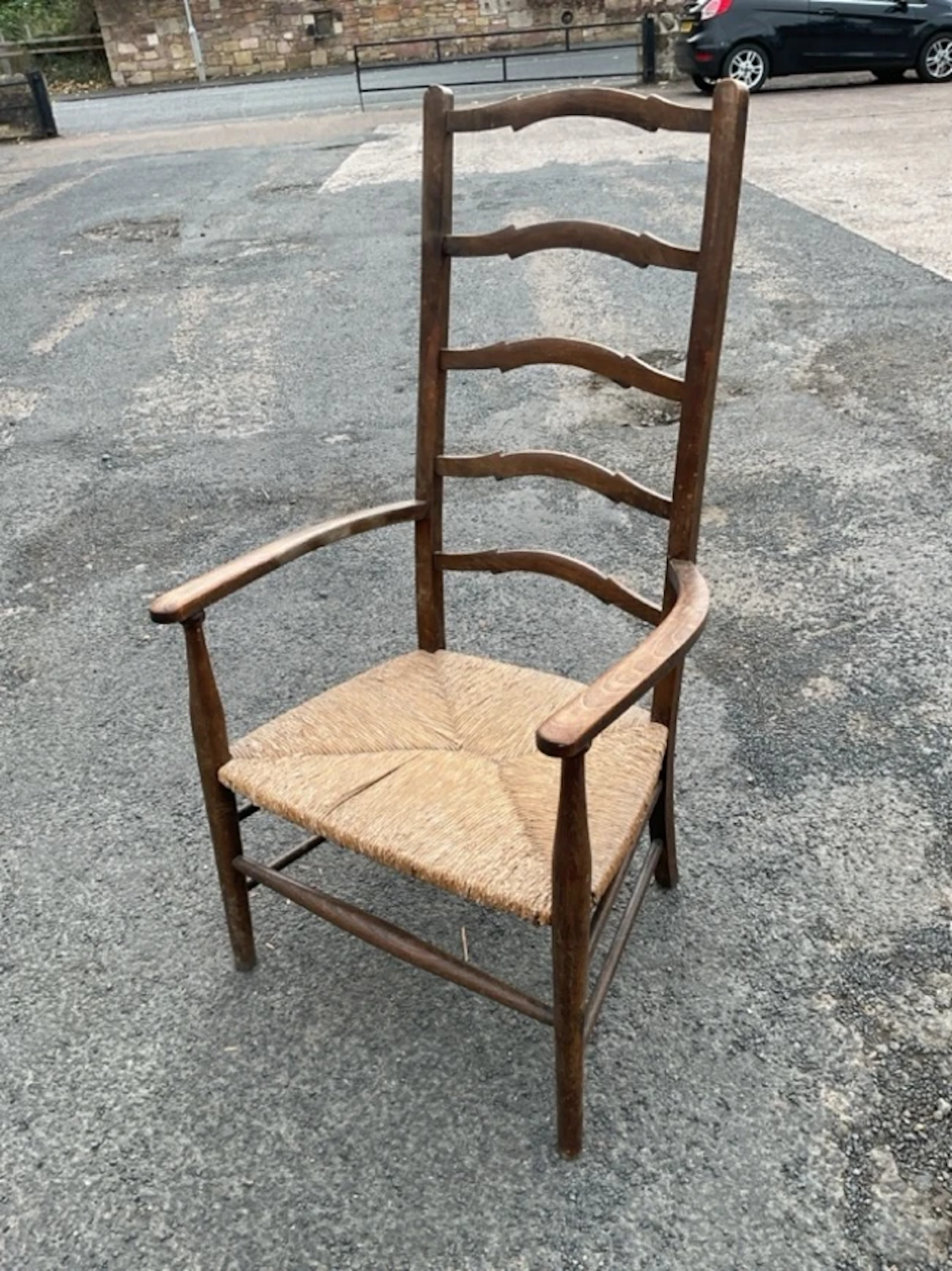 A rush-seated ladderback armchair with five shaped rails and rounded