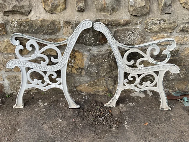 A pair of painted cast iron garden bench ends with scrolled arms and