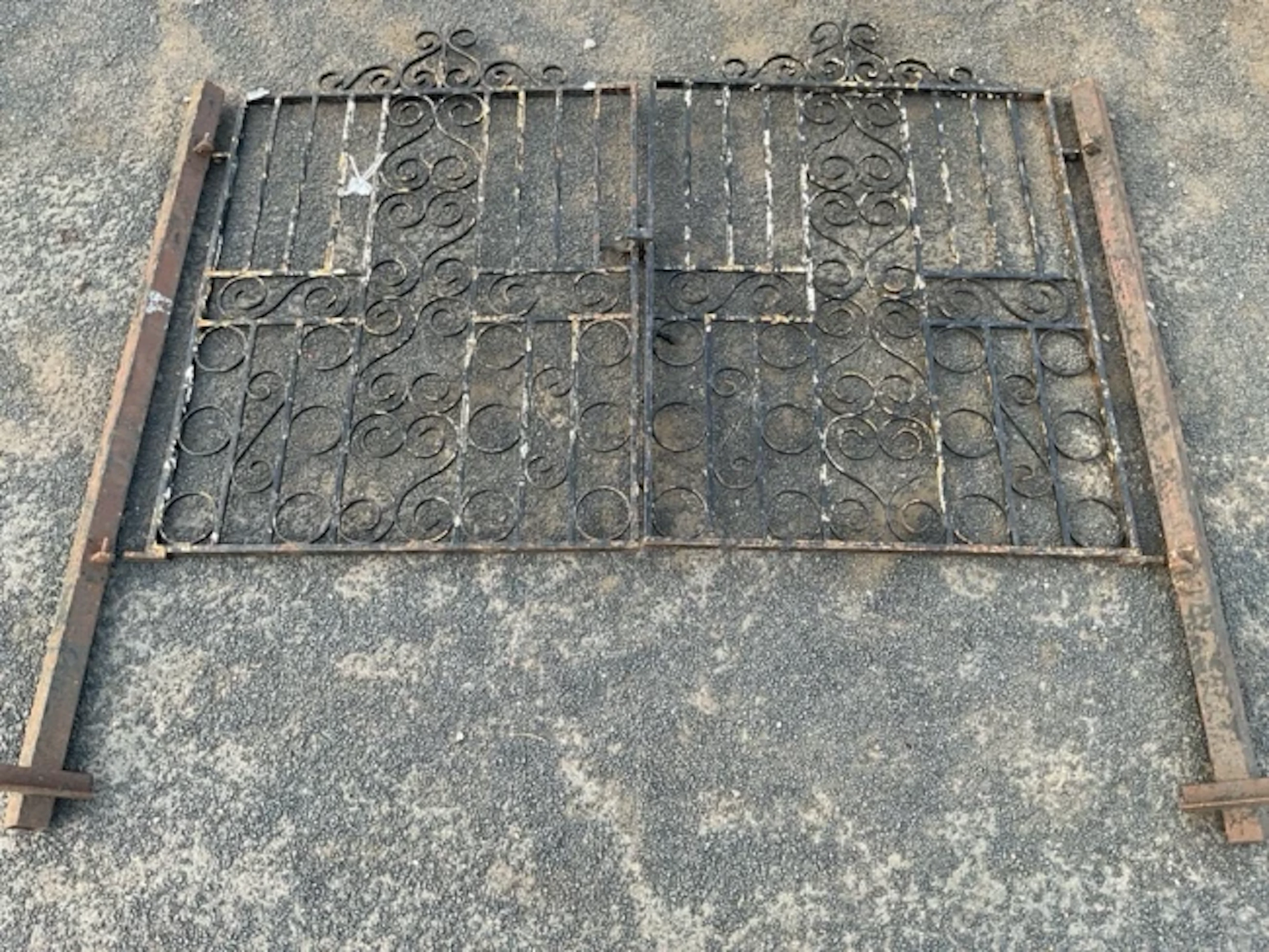 A pair of wrought iron garden gates with scrolled panels and twisted