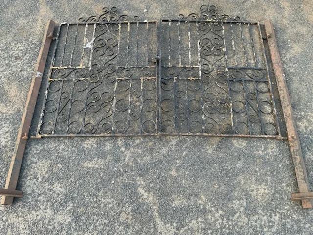 A pair of wrought iron garden gates with scrolled panels and twisted