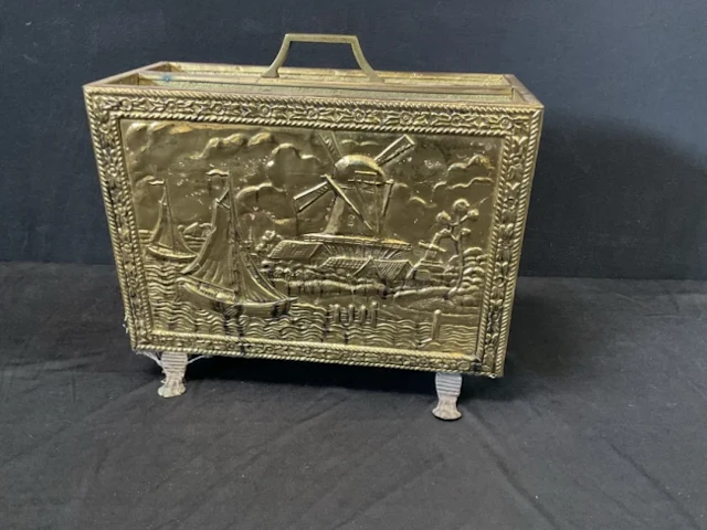 A rectangular brass magazine rack embossed with Dutch canal scene
