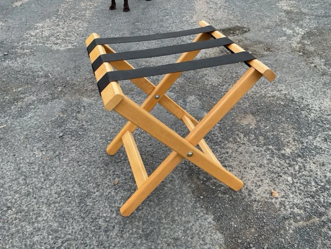 A contemporary folding beech luggage stand with webbing to top, on