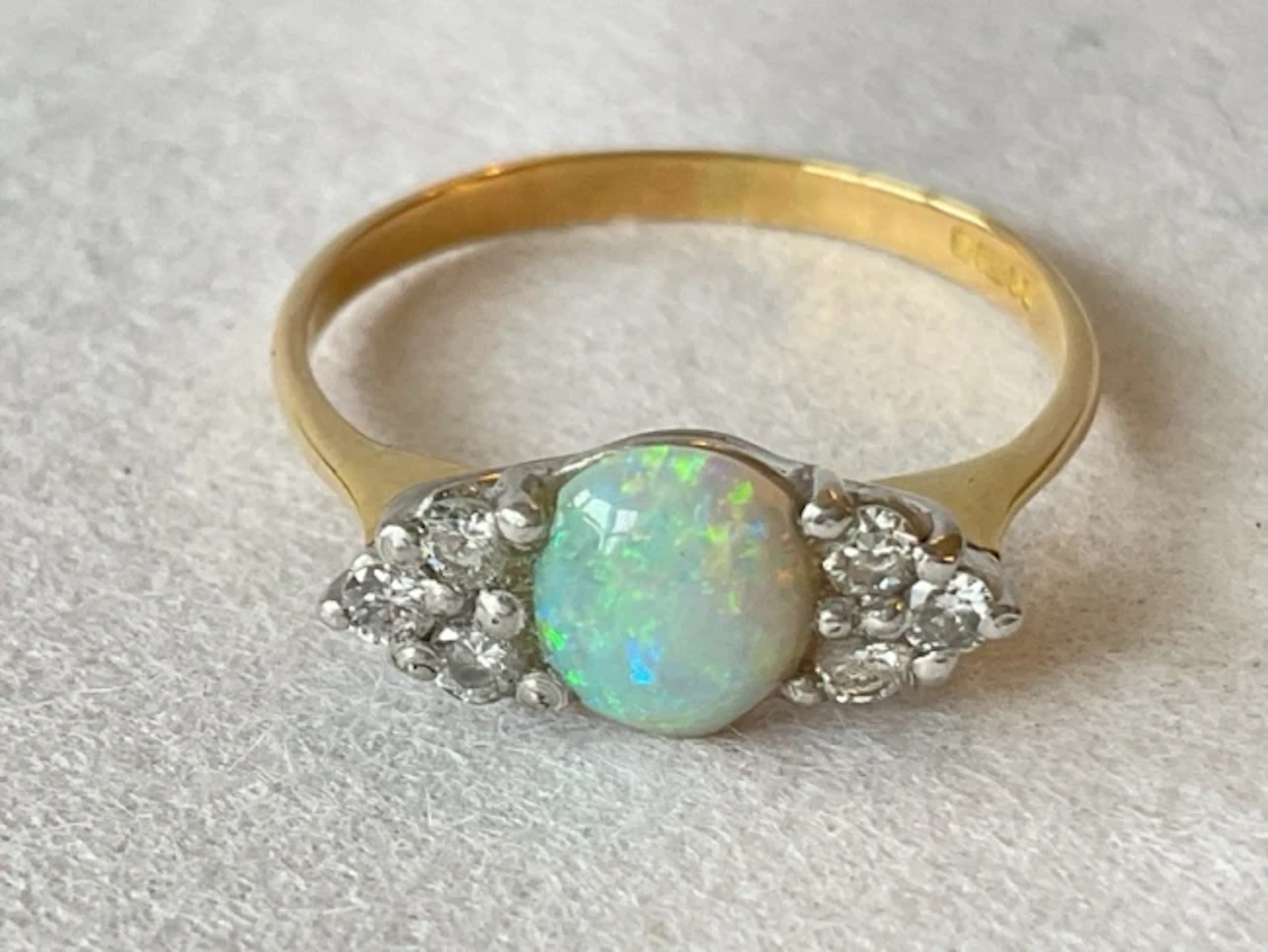 An 18ct gold ring with central cabochon opal flanked by trios of diamonds