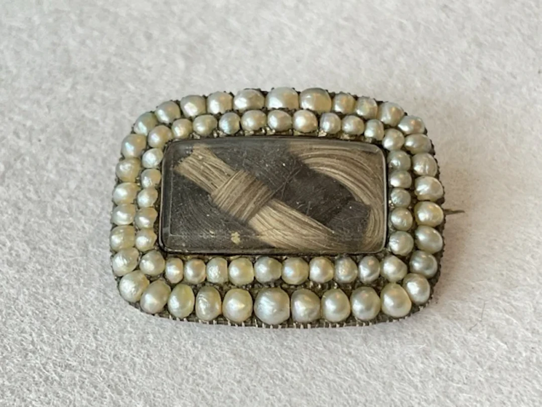 An antique gold mourning brooch with plaited locks of hair framed