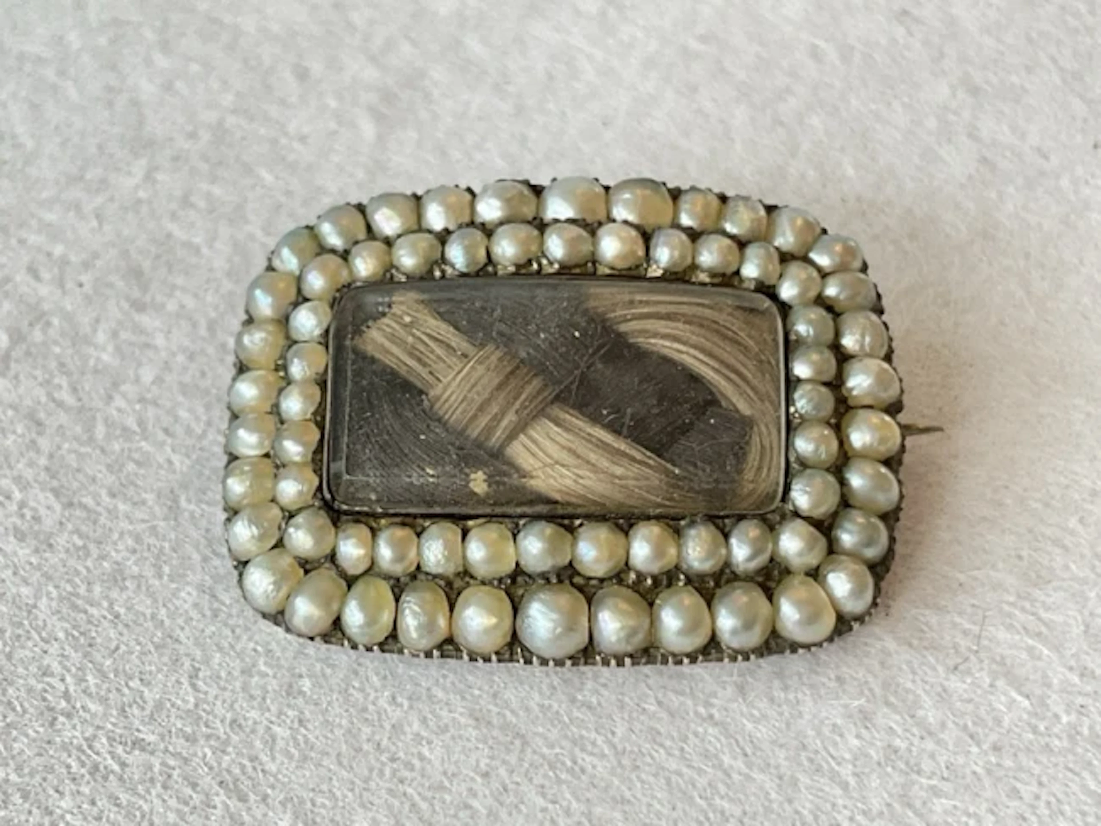 An antique gold mourning brooch with plaited locks of hair framed