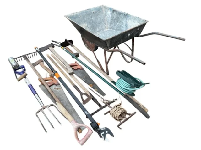 Miscellaneous garden tools - a wheelbarrow, rakes, axes, saws, a fork