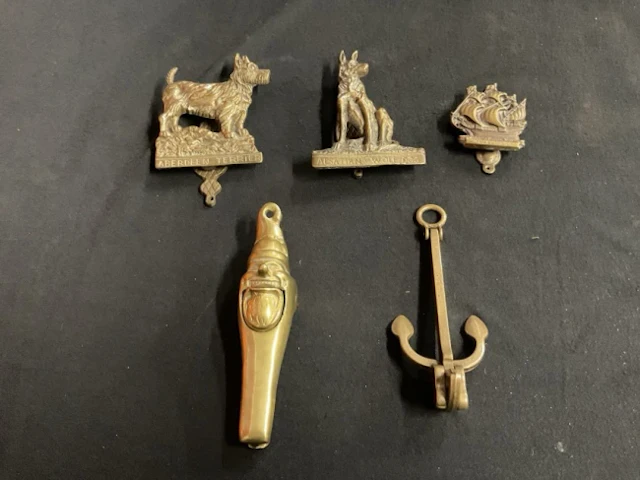 Three cast brass door knockers in the form of a terrier, an alsatian