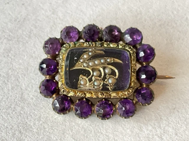 A Victorian gold memorial brooch, with amethysts framing a seed pearl