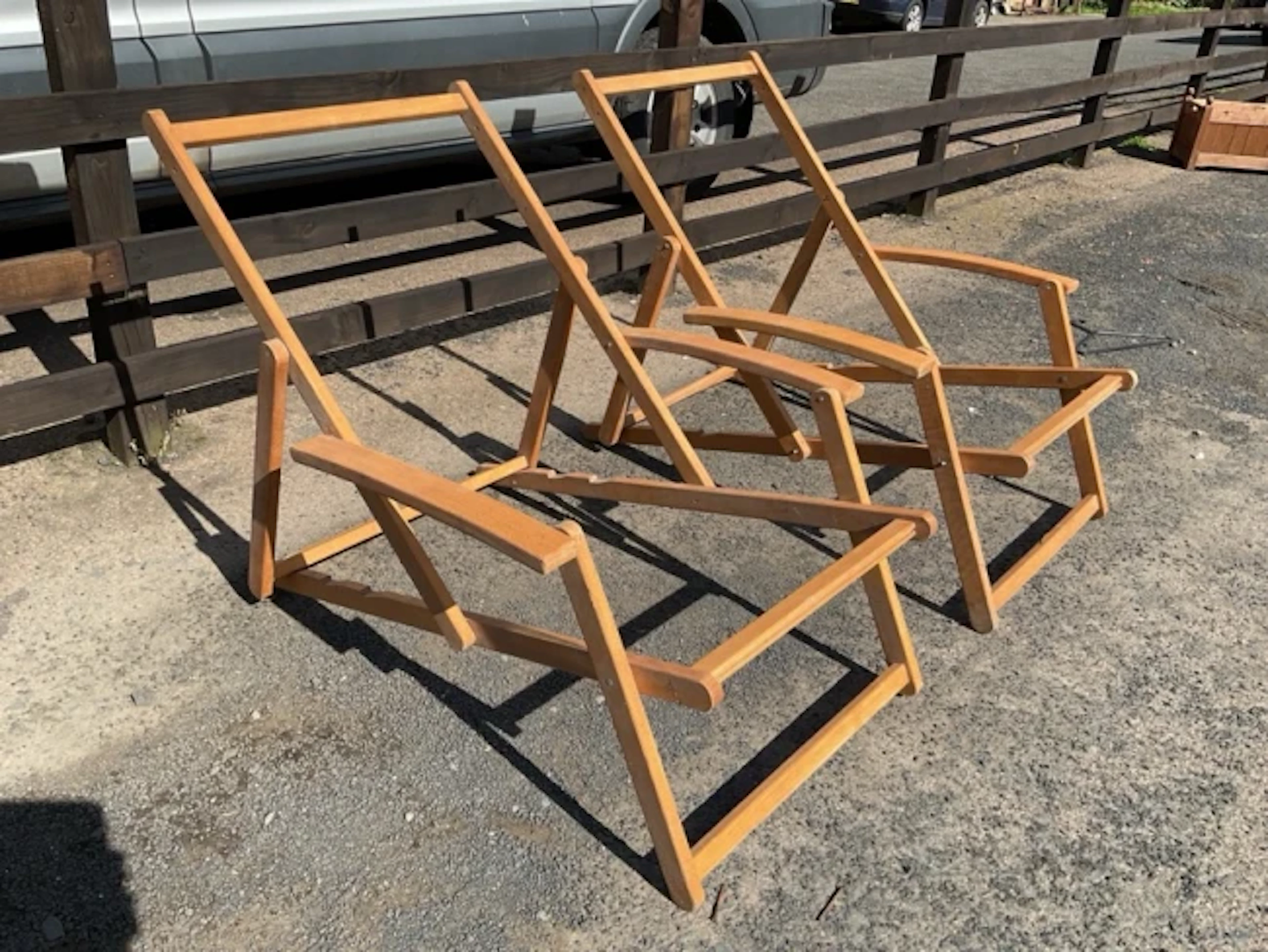 A pair of folding beech deck-type armchairs with adjustable ratchet