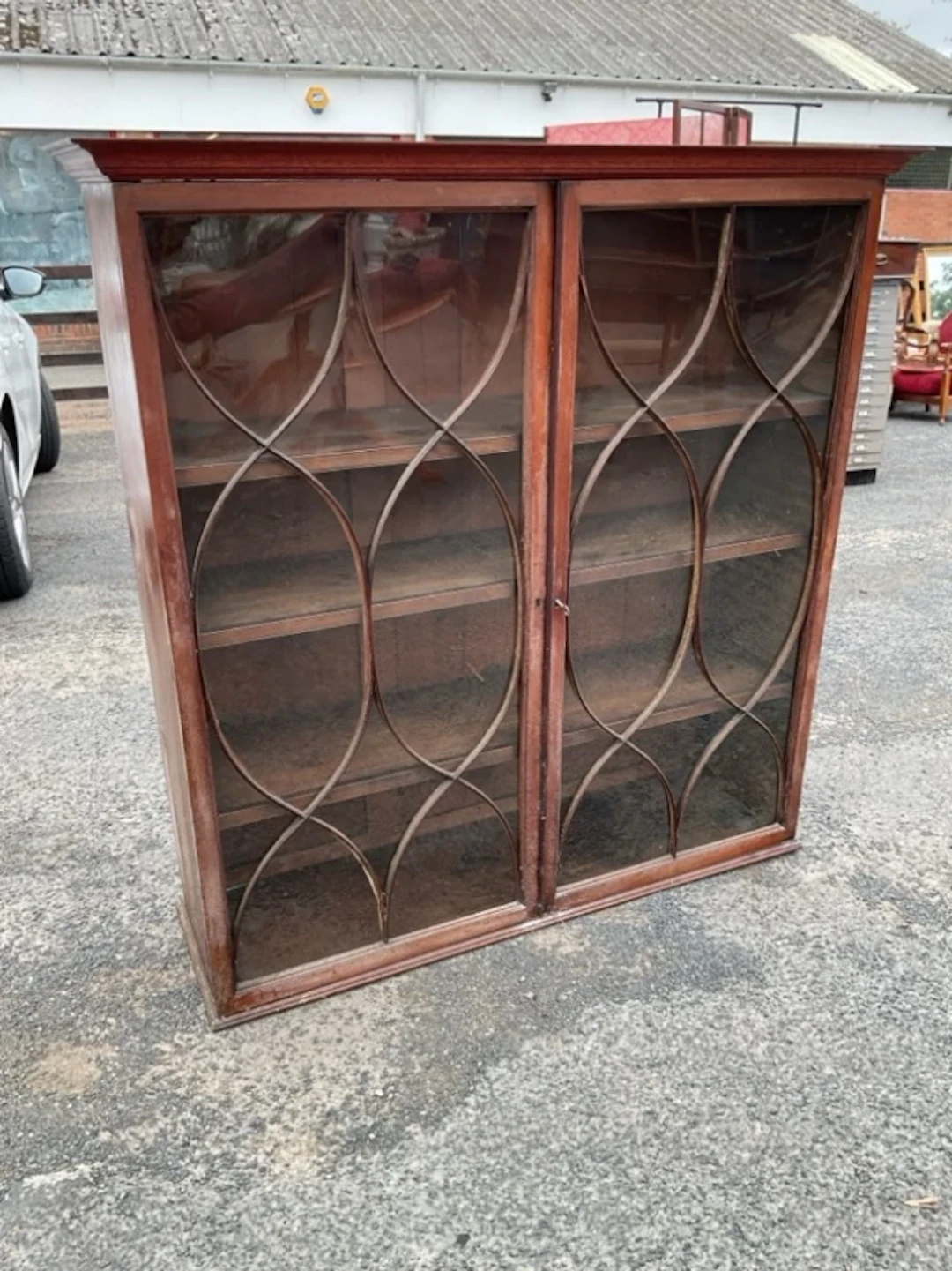 An antique glazed mahogany cabinet with ogee cornice above astragel