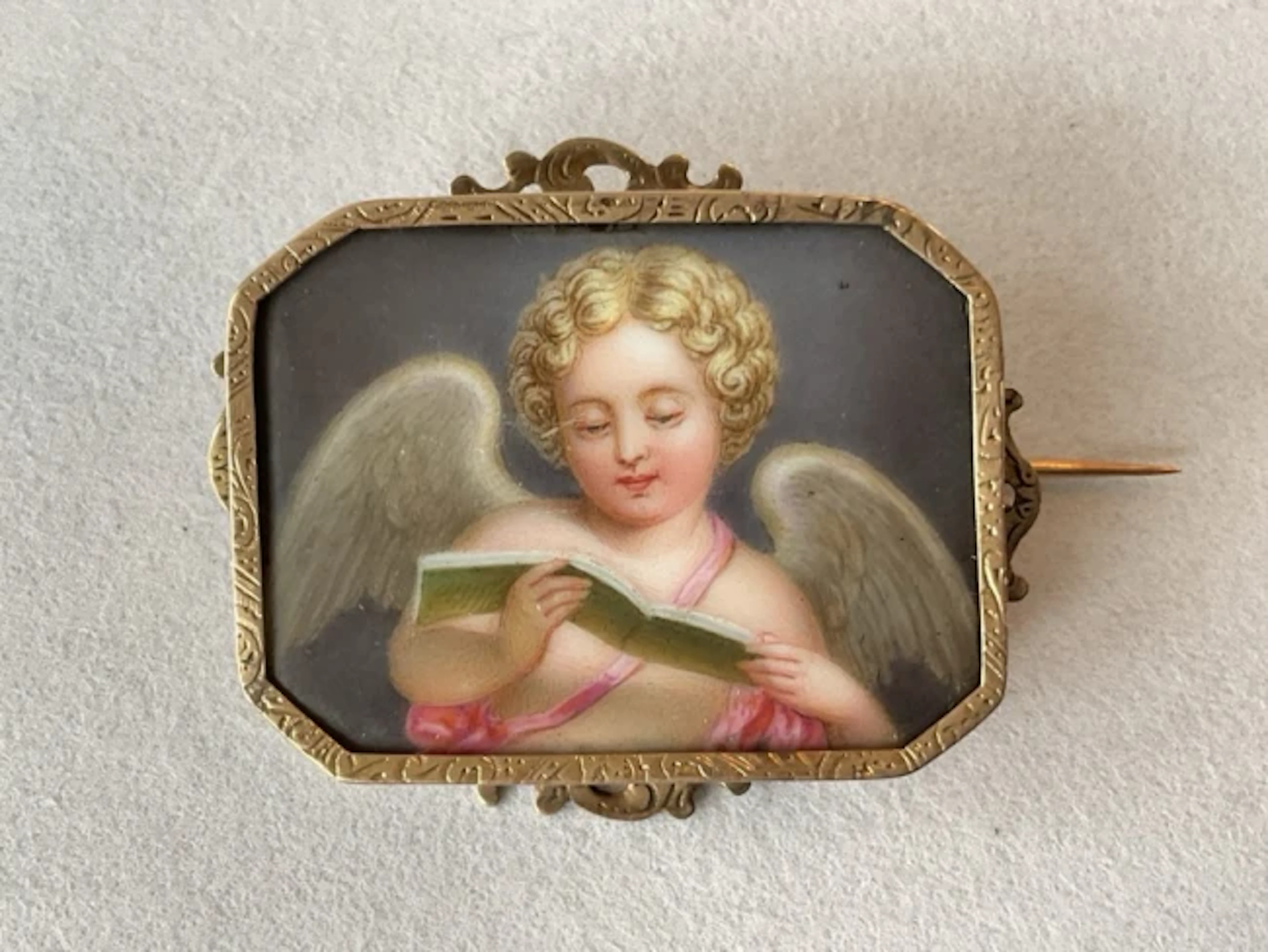 A Victorian miniature enamelled porcelain plaque of a Cupid reading