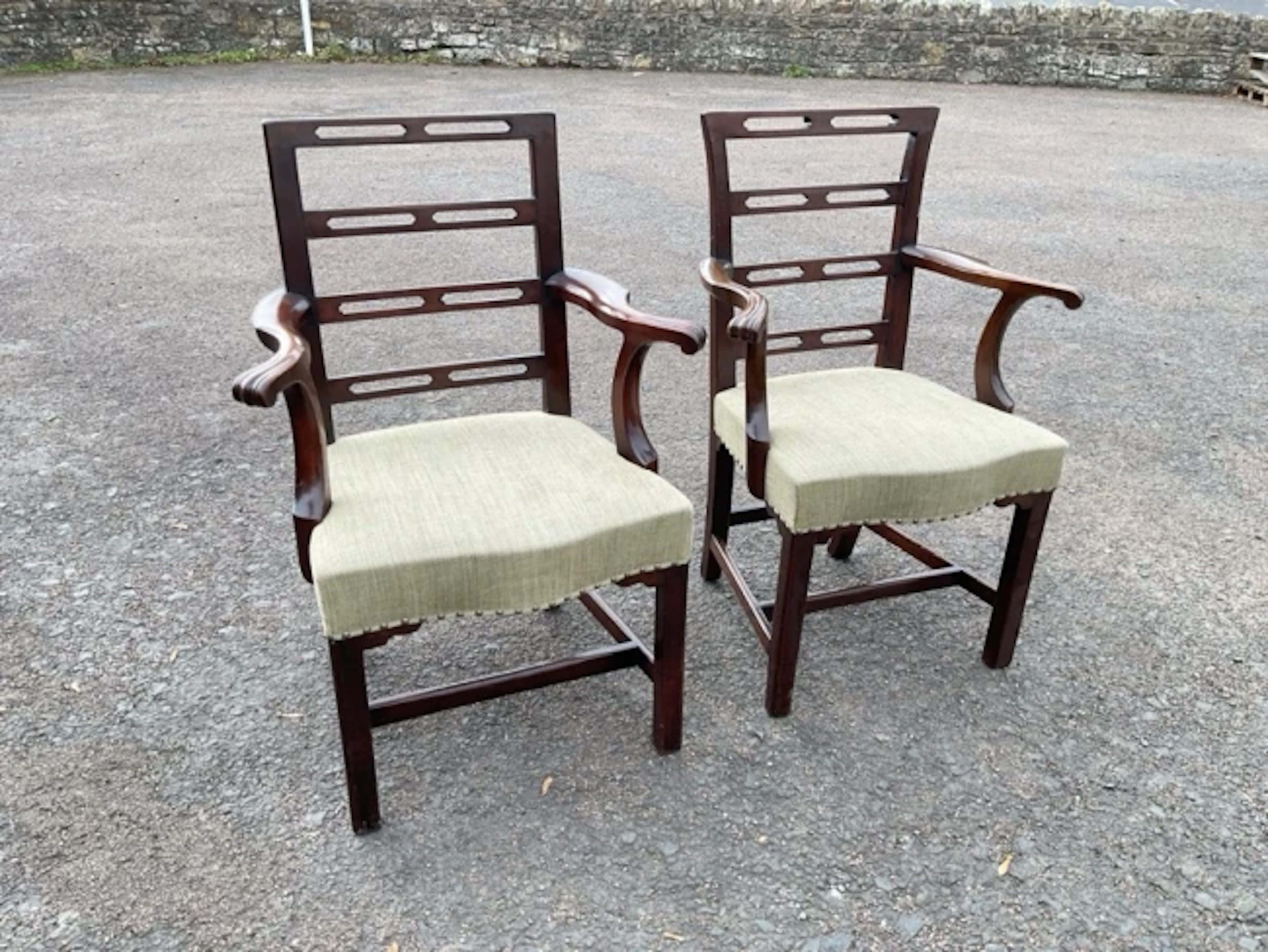 A pair of antique mahogany elbow chairs with pierced ladderbacks and