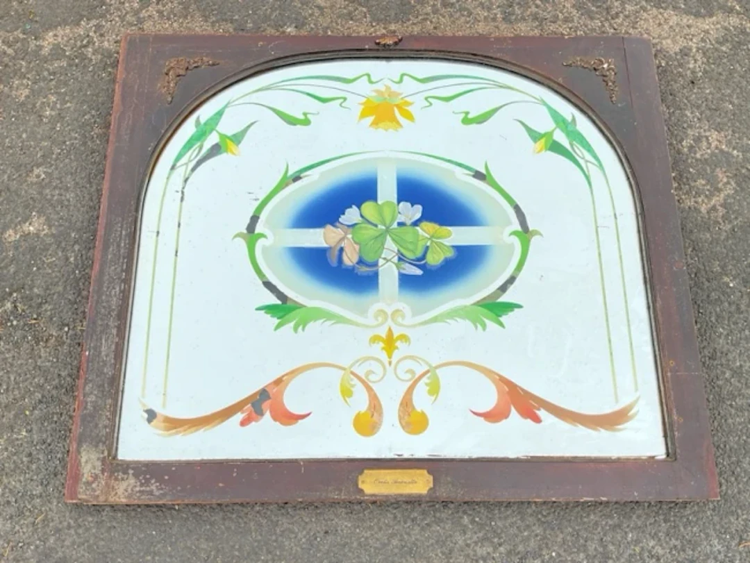 An arched mirror panel with reverse painted floral decoration titled