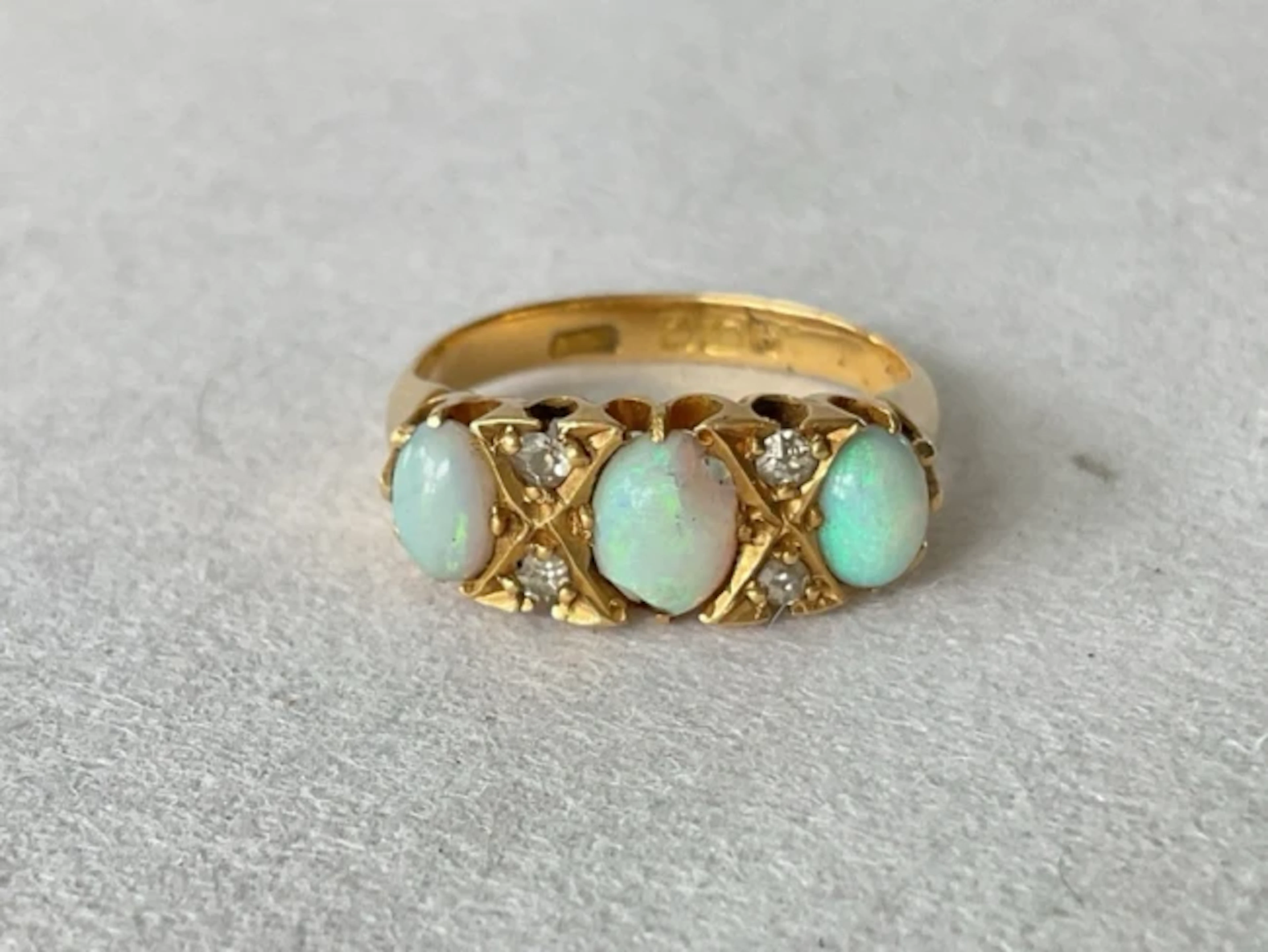 An antique 18ct gold ring having trilogy of cabochon opals, each separated
