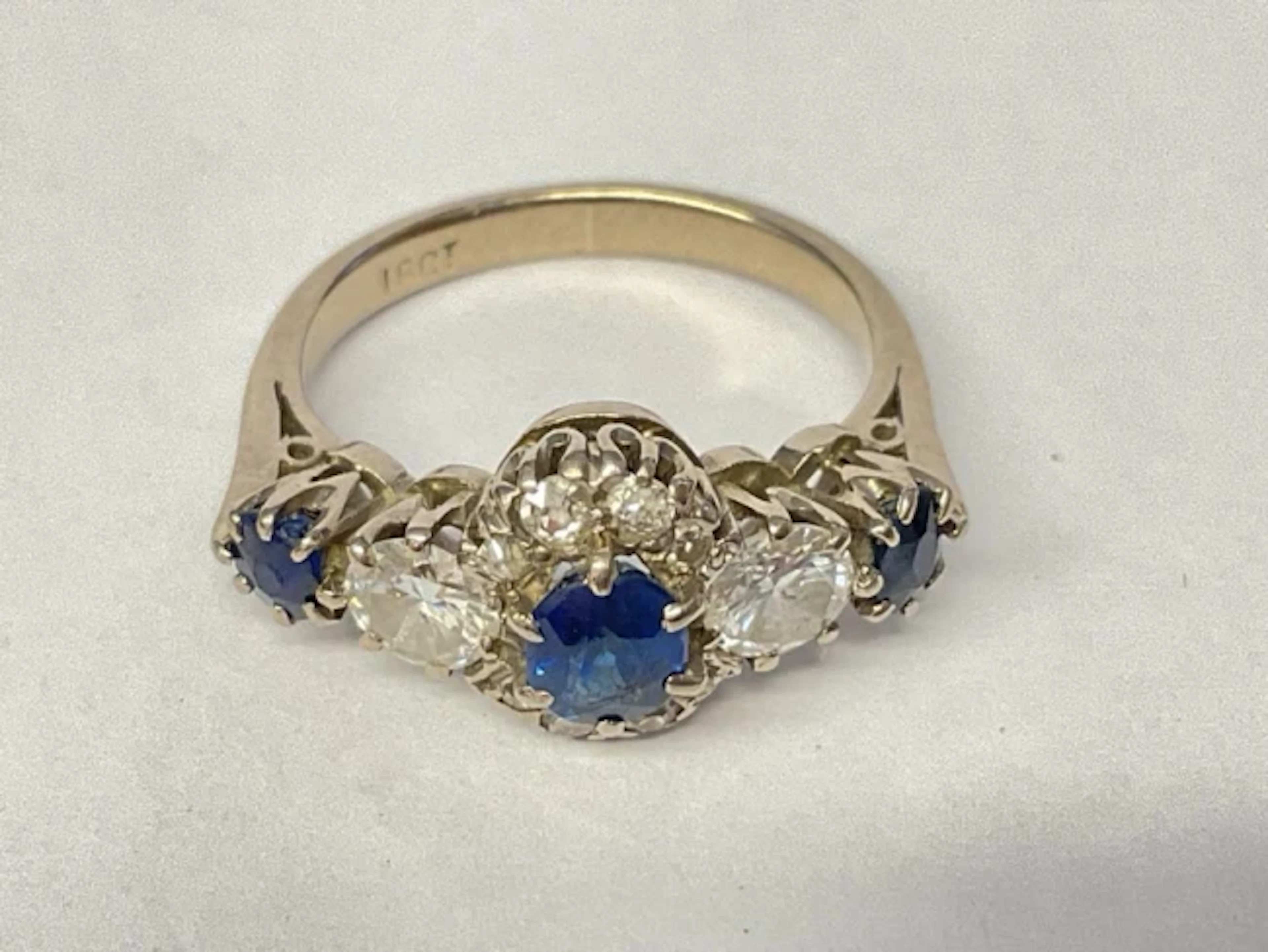 An 18ct white gold sapphire and diamond ring, claw set with trilogy