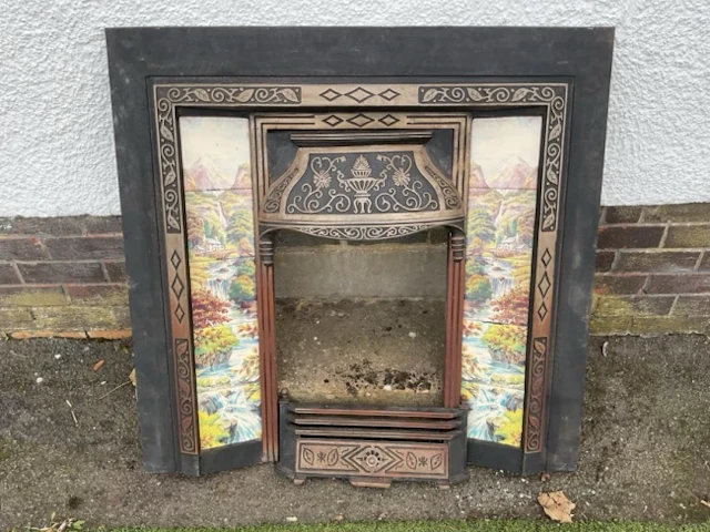A Victorian style cast iron fire inset with foliate scrolled hood