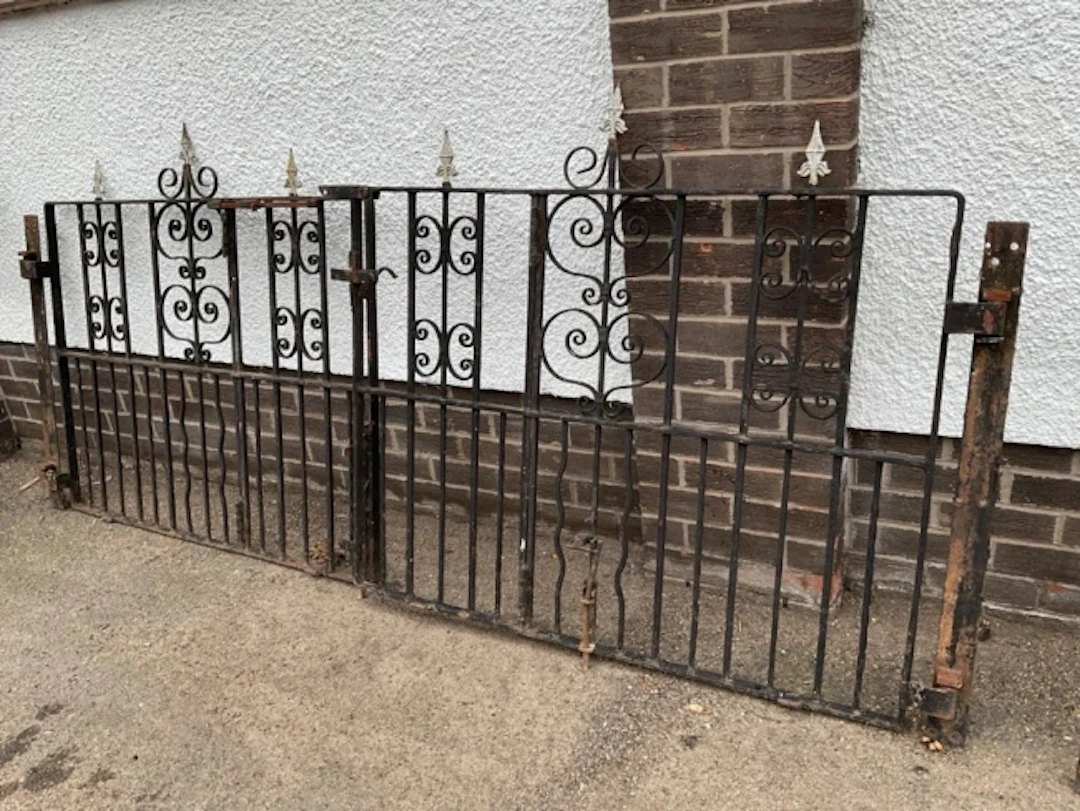 A pair of wrought iron driveway gates with spear finials on panels