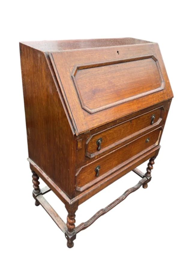 An oak bureau with panelled fall-front enclosing a fitted interior