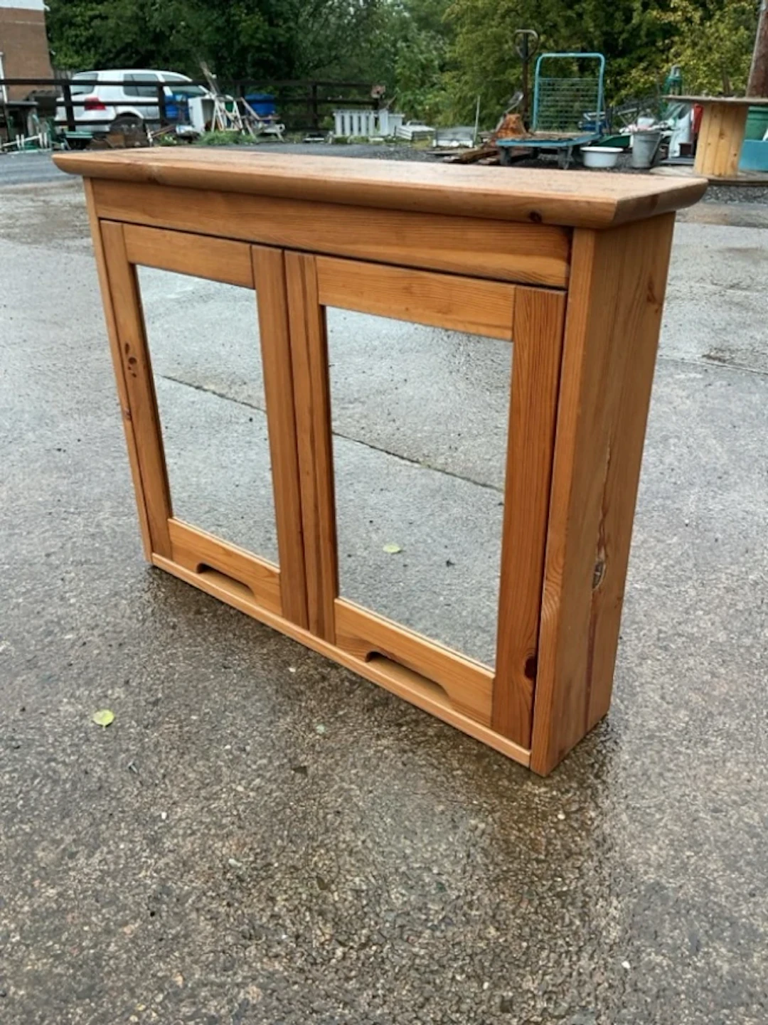 A pine bathroom cabinet with mirror doors, having interior with two