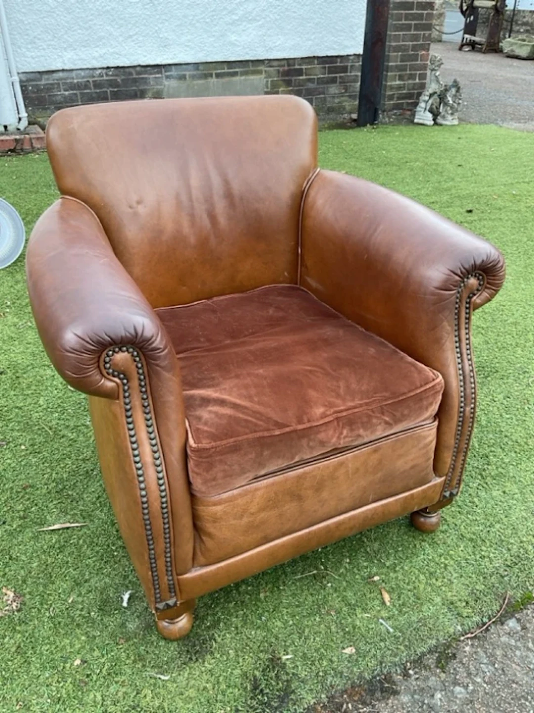 A leather upholstered tub armchair with padded back & arms framing