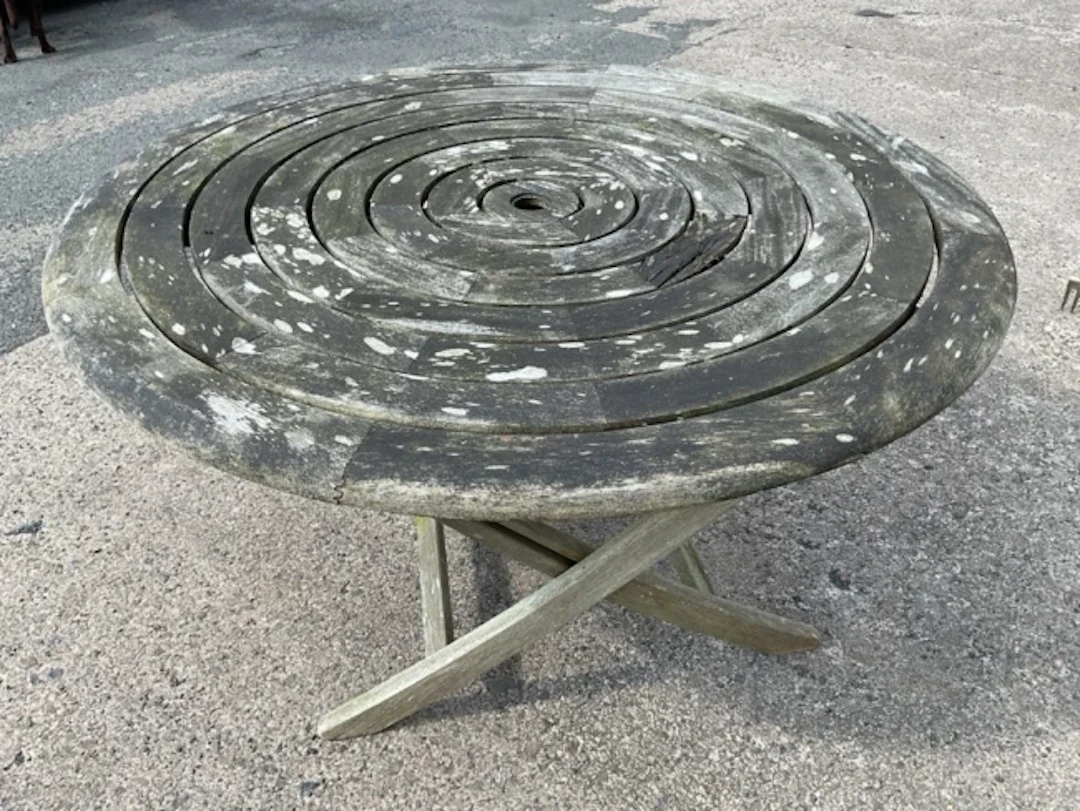 A circular teak folding garden table by Alexander Rose, with graduated