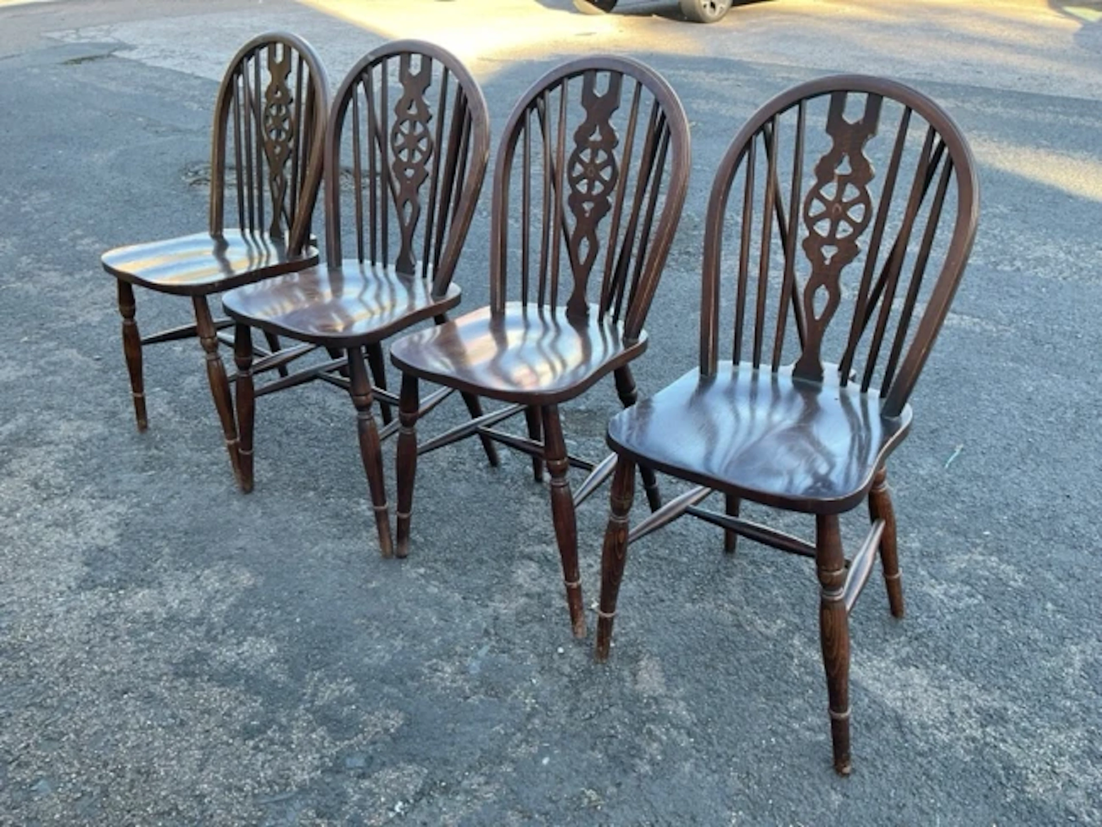 A set of four stained hardwood wheelback chairs, the hooped backs