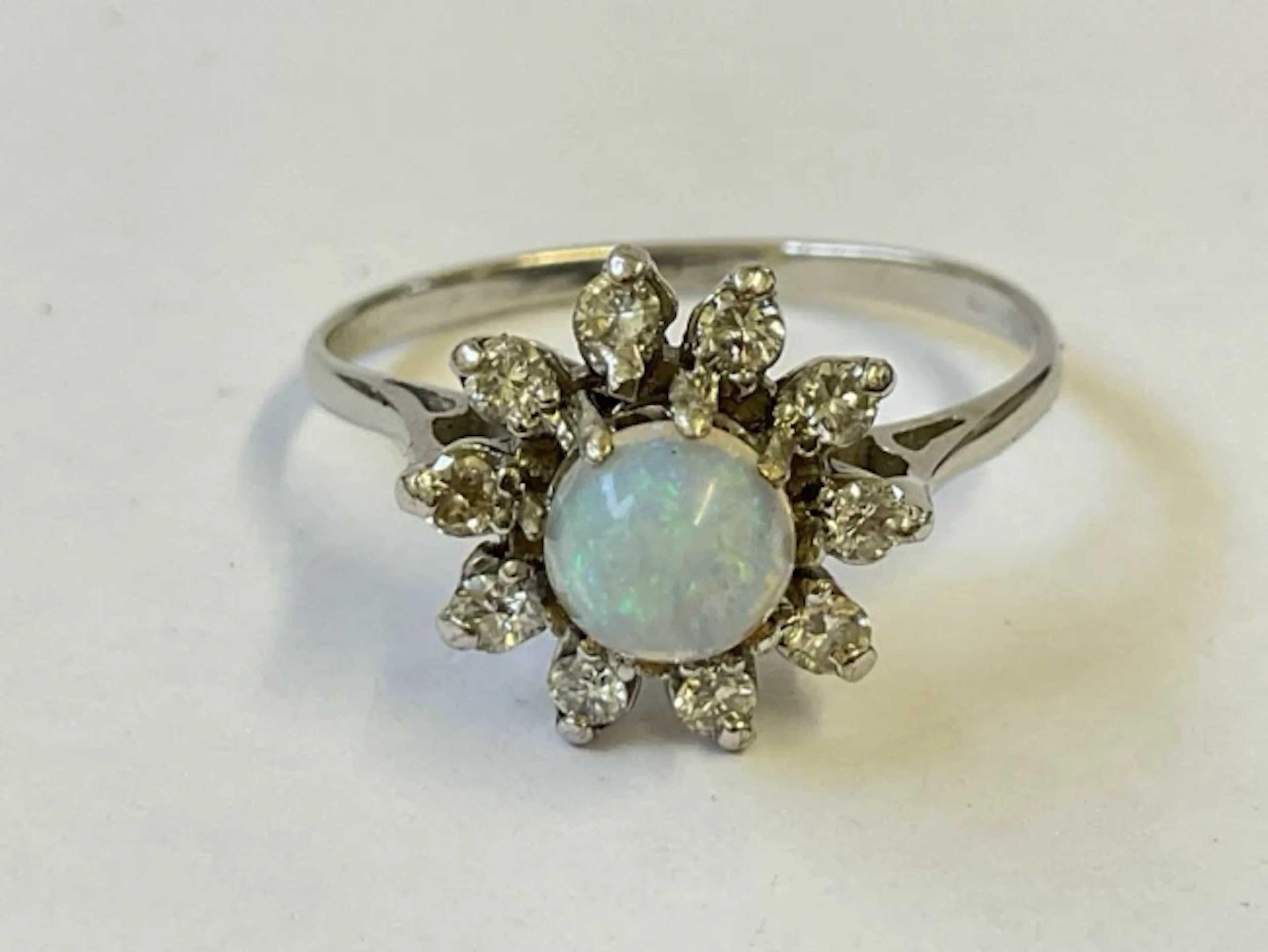 An antique 18ct white gold cluster ring with central raised opal cabochon