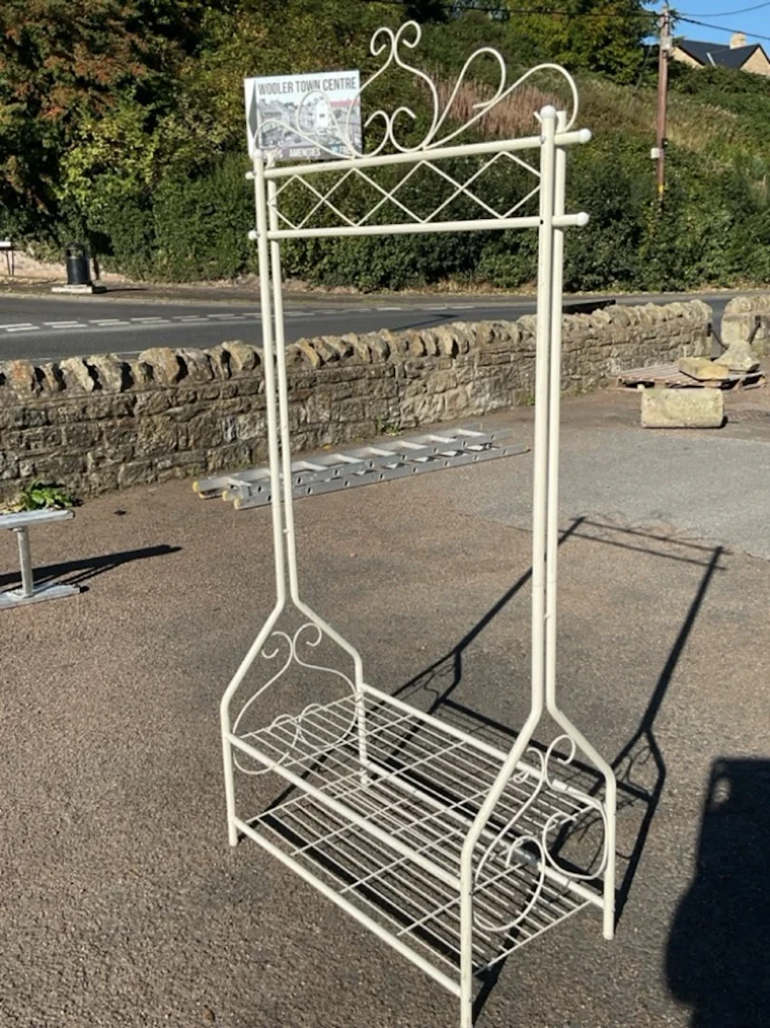 A painted metal clothes stand with scrolled wirework decoration, having