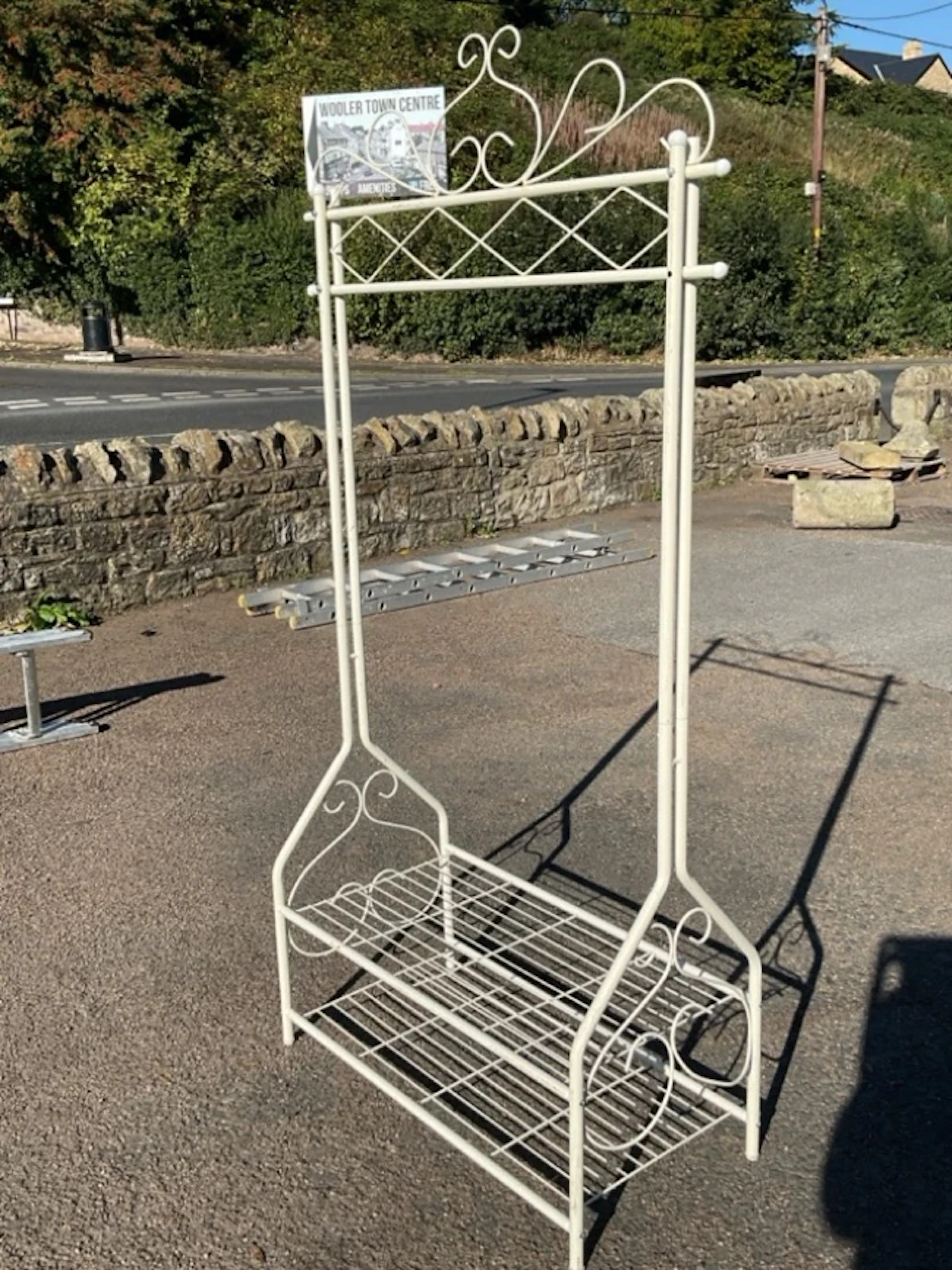 A painted metal clothes stand with scrolled wirework decoration, having