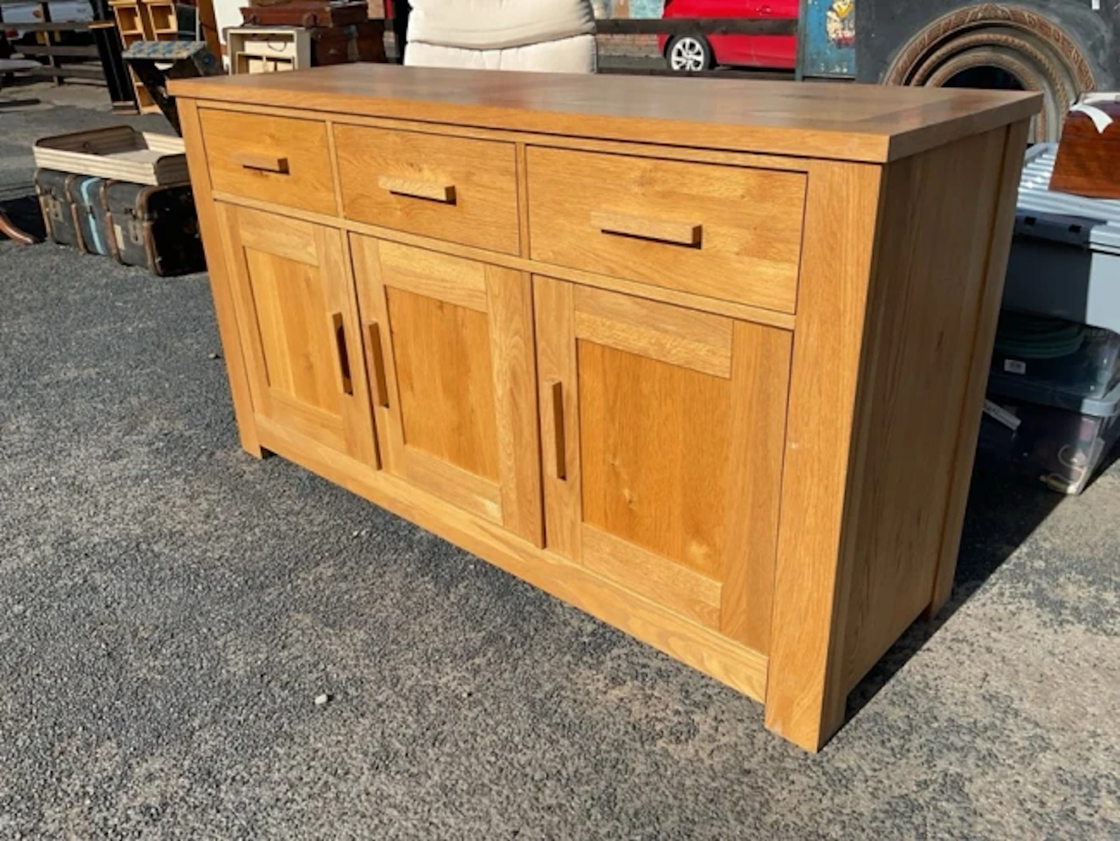 A contemporary oak dresser with three frieze drawers above panelled