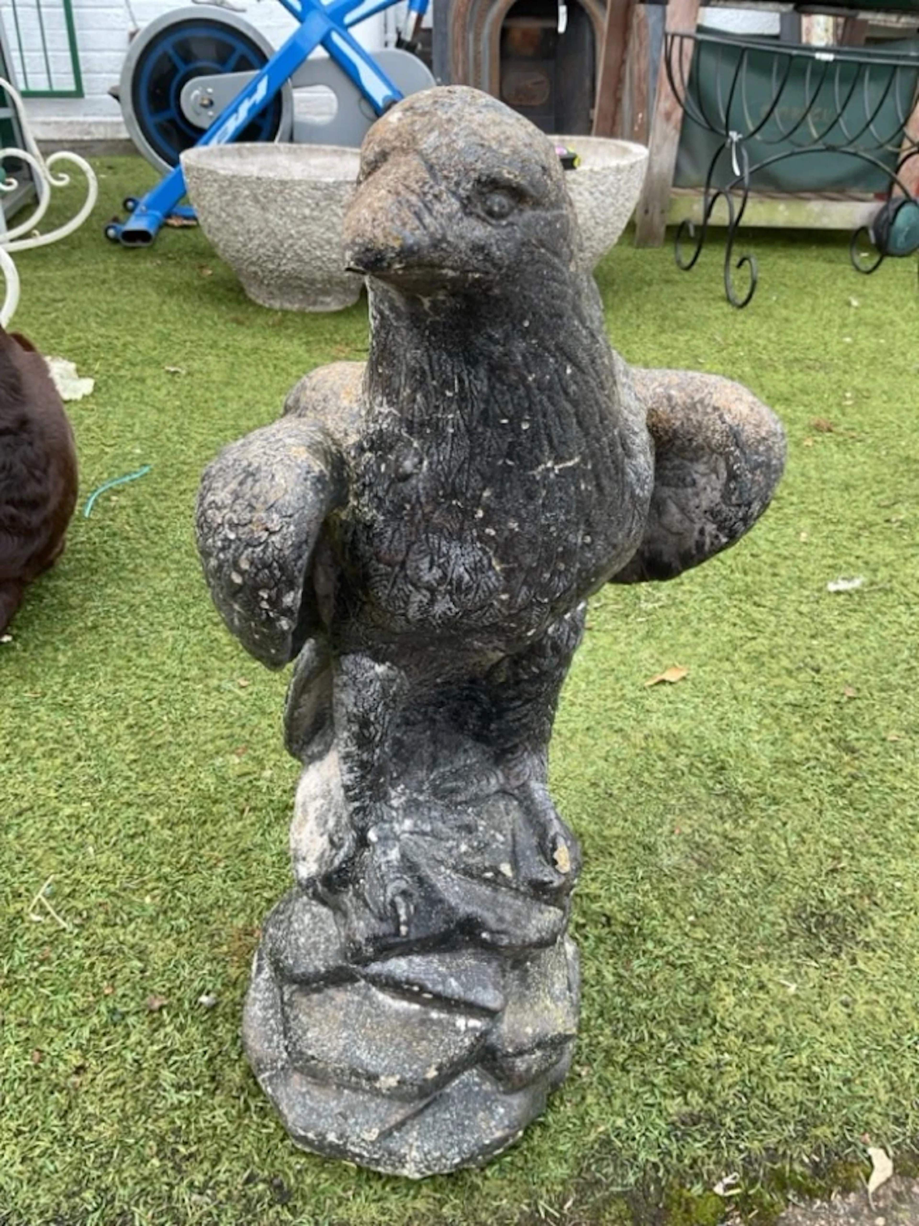 A painted composition stone eagle, the bird standing on rocky outcrop. (23.5in)