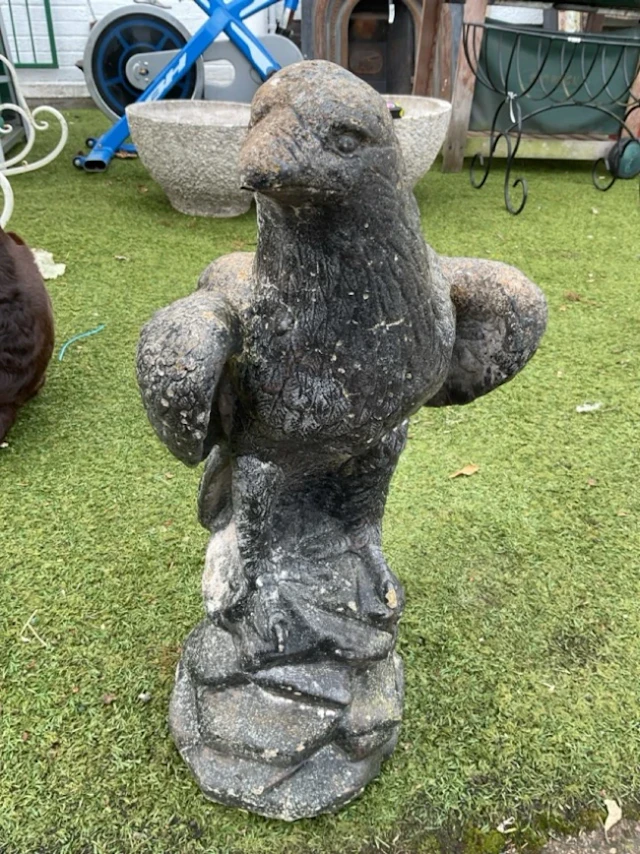 A painted composition stone eagle, the bird standing on rocky outcrop. (23.5in)