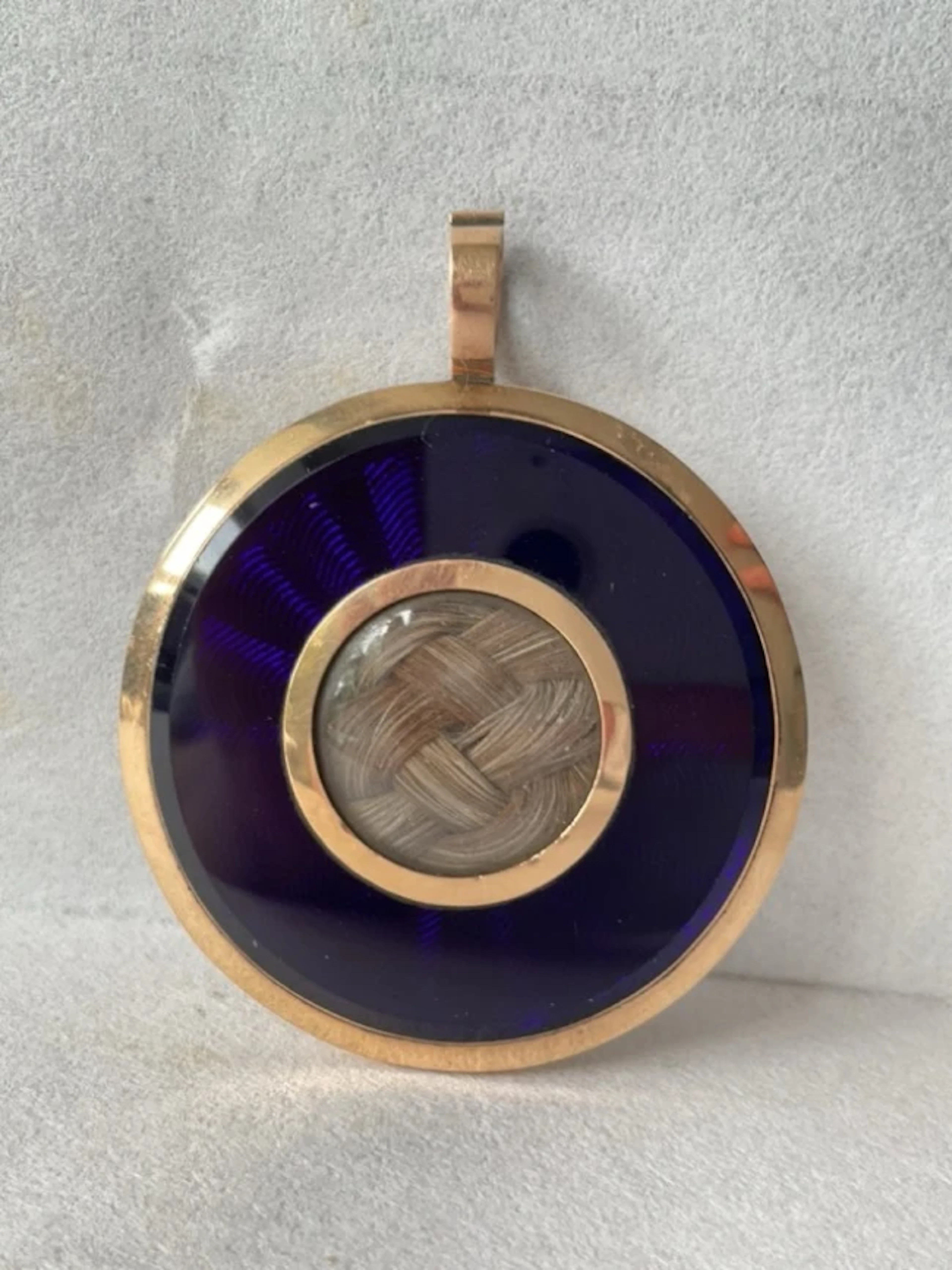 A C19th gold memorial pendant having plaited hair with engine turned