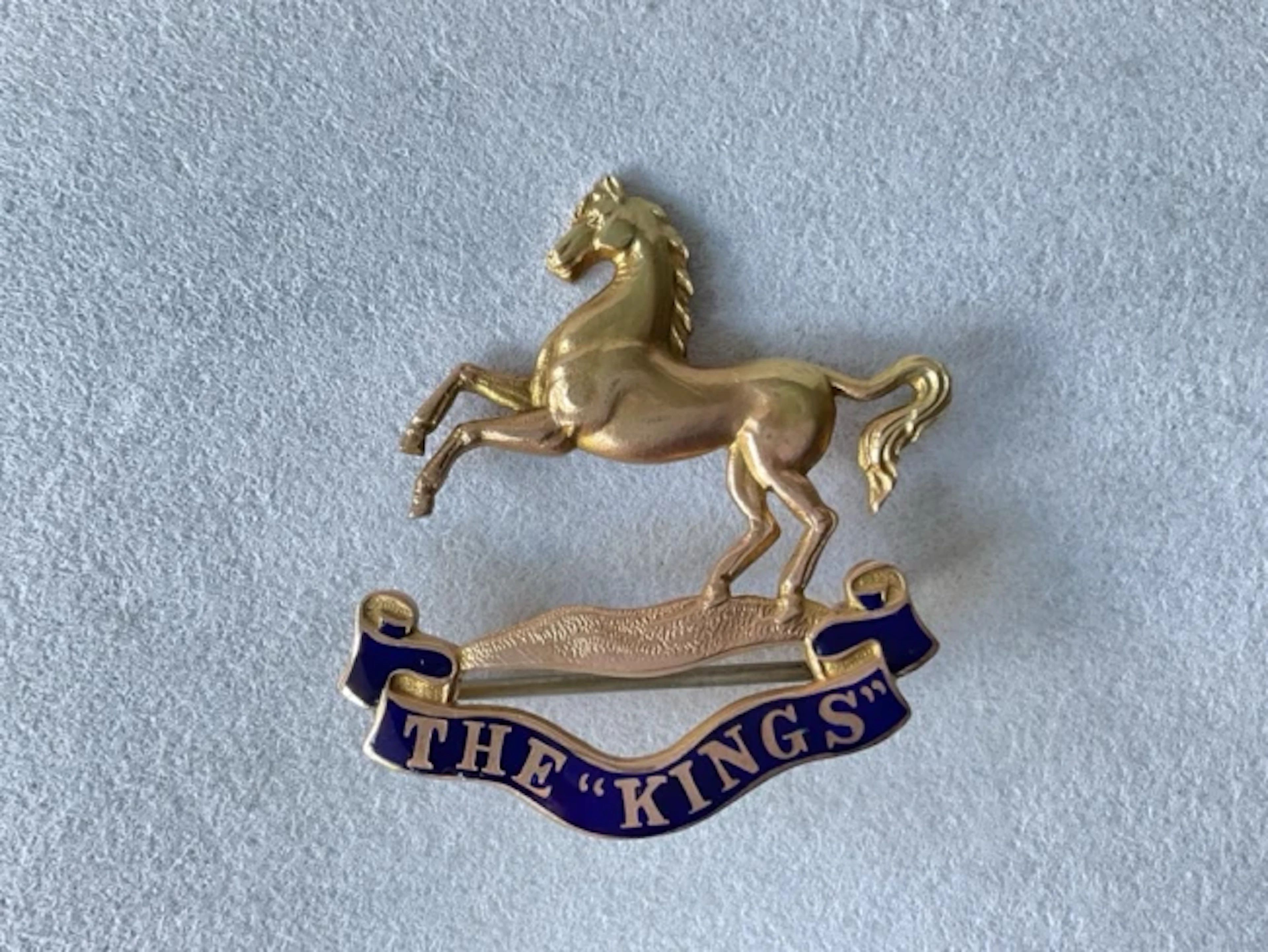 A 9ct gold sweetheart brooch for the Kings Regiment, with blue enamelled