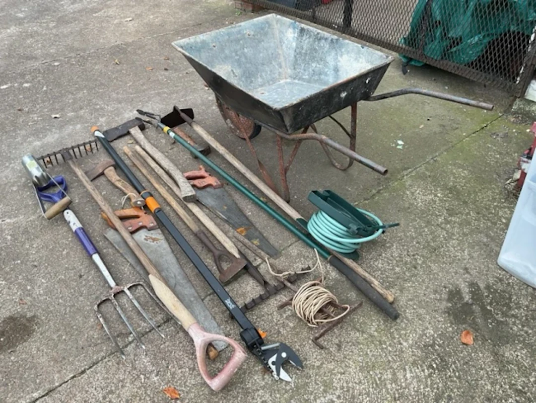 Miscellaneous garden tools - a wherlbarrow, rakes, axes, saws, a fork