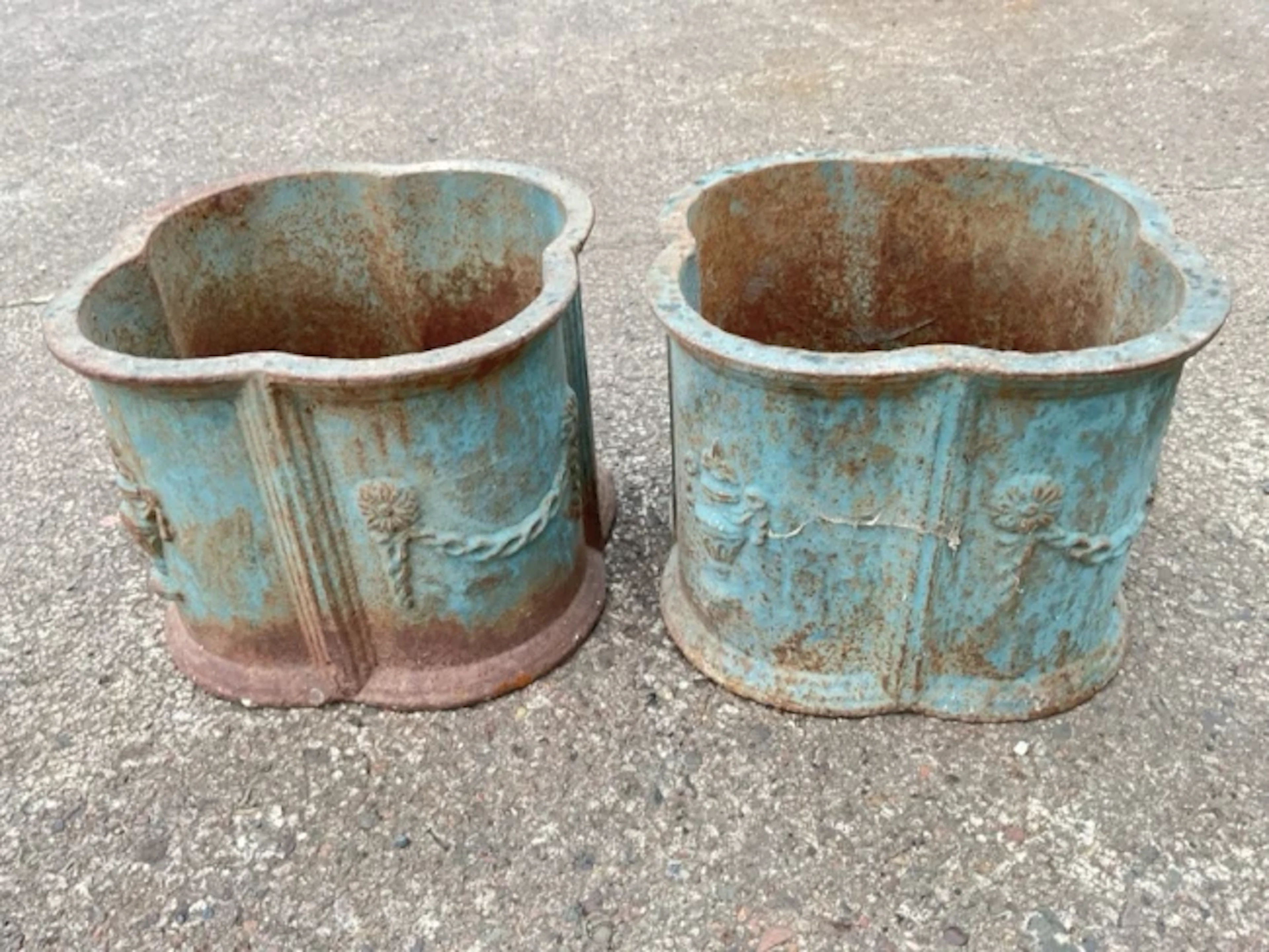 A pair of cast iron garden pots of quatrefoil shape decorated with