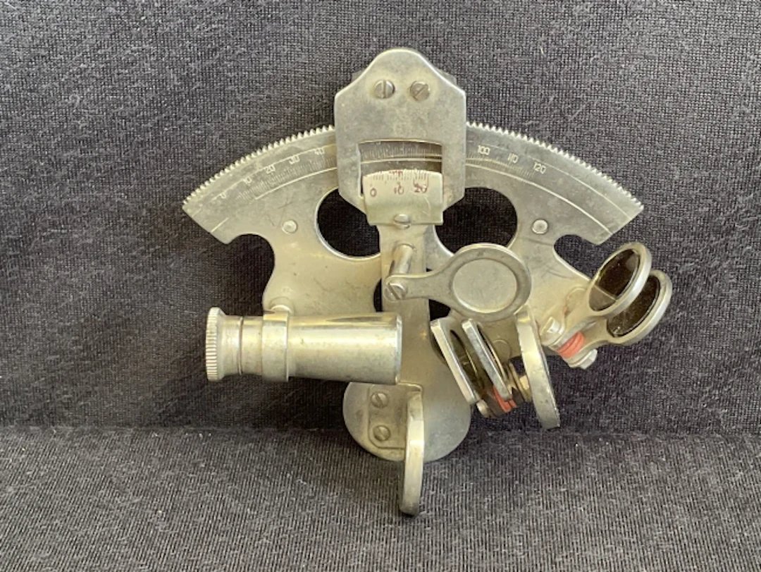 A miniature chromed brass sextant with glass filters and curved scale