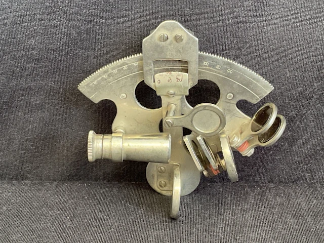 A miniature chromed brass sextant with glass filters and curved scale