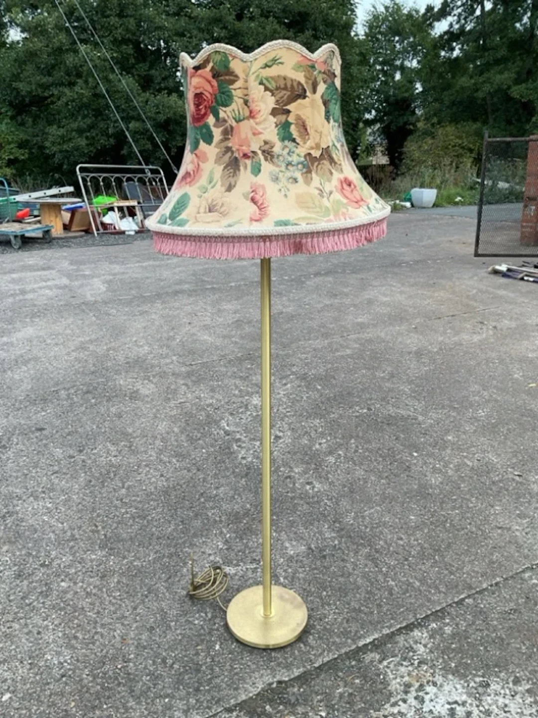 A brass standard lamp with scalloped floral chintz shade on a tubular