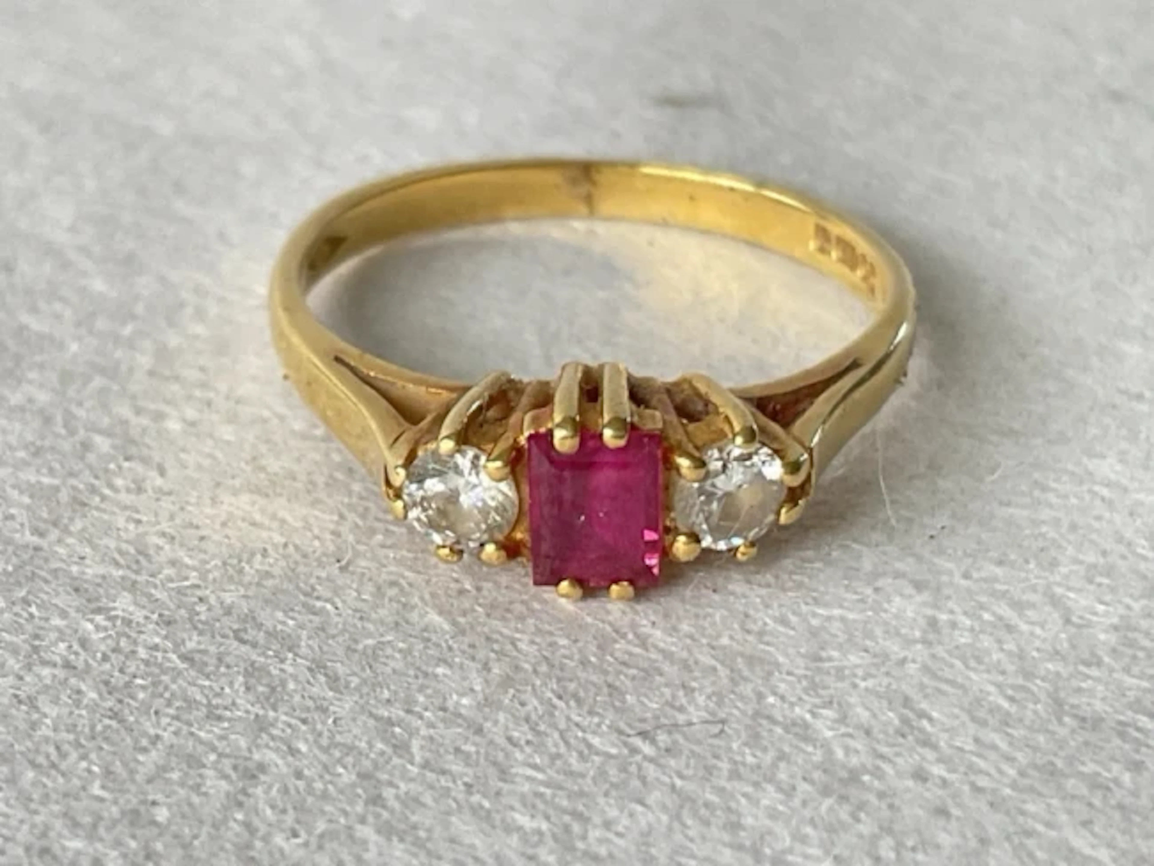 An 18ct gold ruby ring, the central emerald cut stone flanked by a